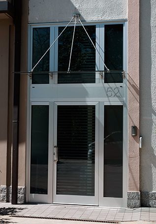 Brushed Aluminium Condominium Doors with Five Fixed Mirrors and Hinged Door One Door House Number Engraved in the Structure and Glass Canopy with Steel Tie Rods