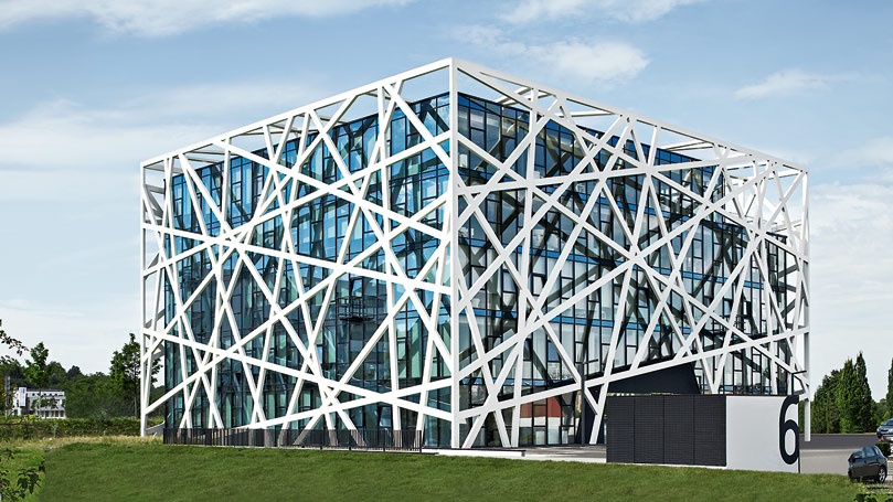 metal structure surrounding a modern glass and steel building